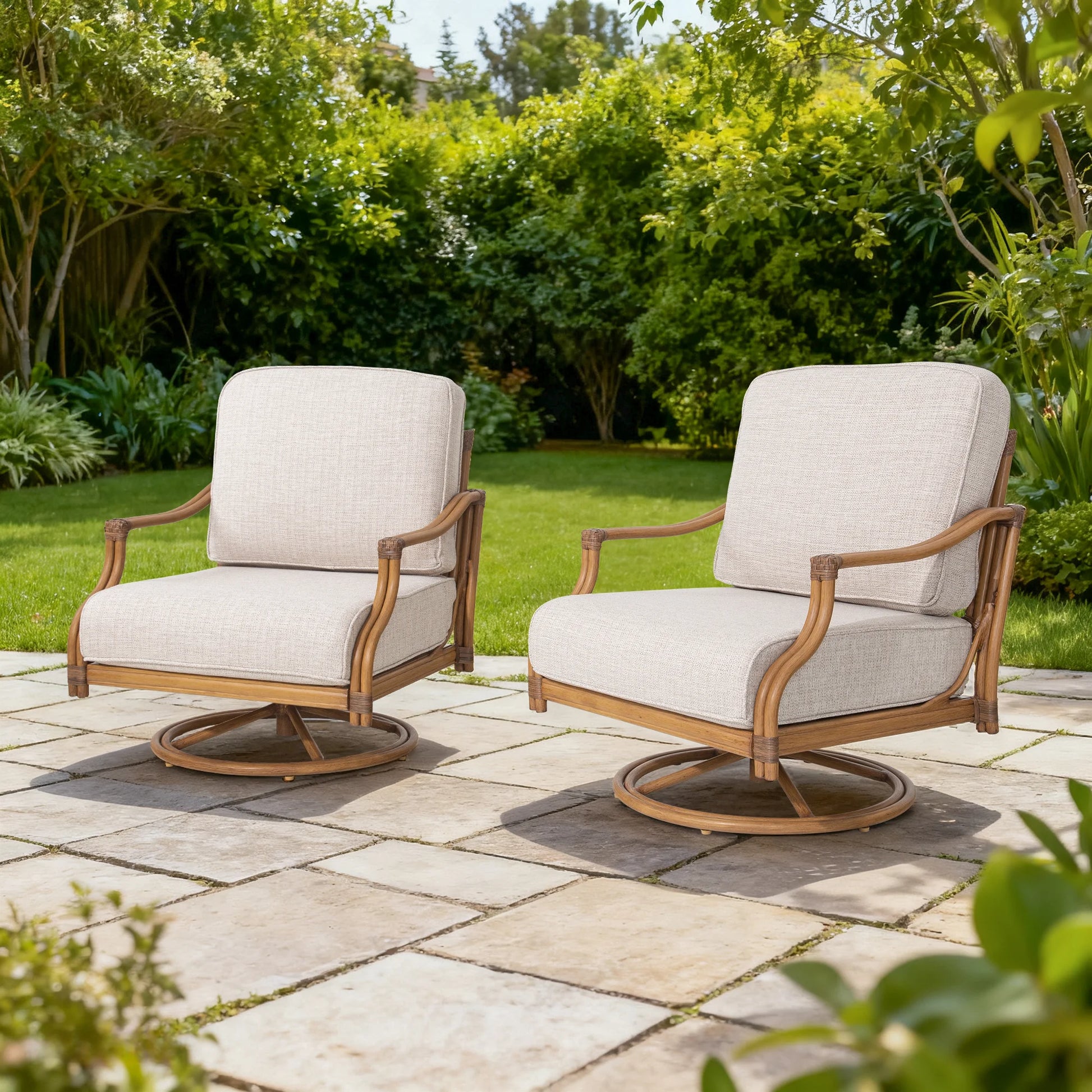 Two beige cushioned chairs with aluminum frames on a stone patio surrounded by greenery.