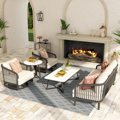 Outdoor patio set with chairs, table, and fireplace in a well-decorated garden.