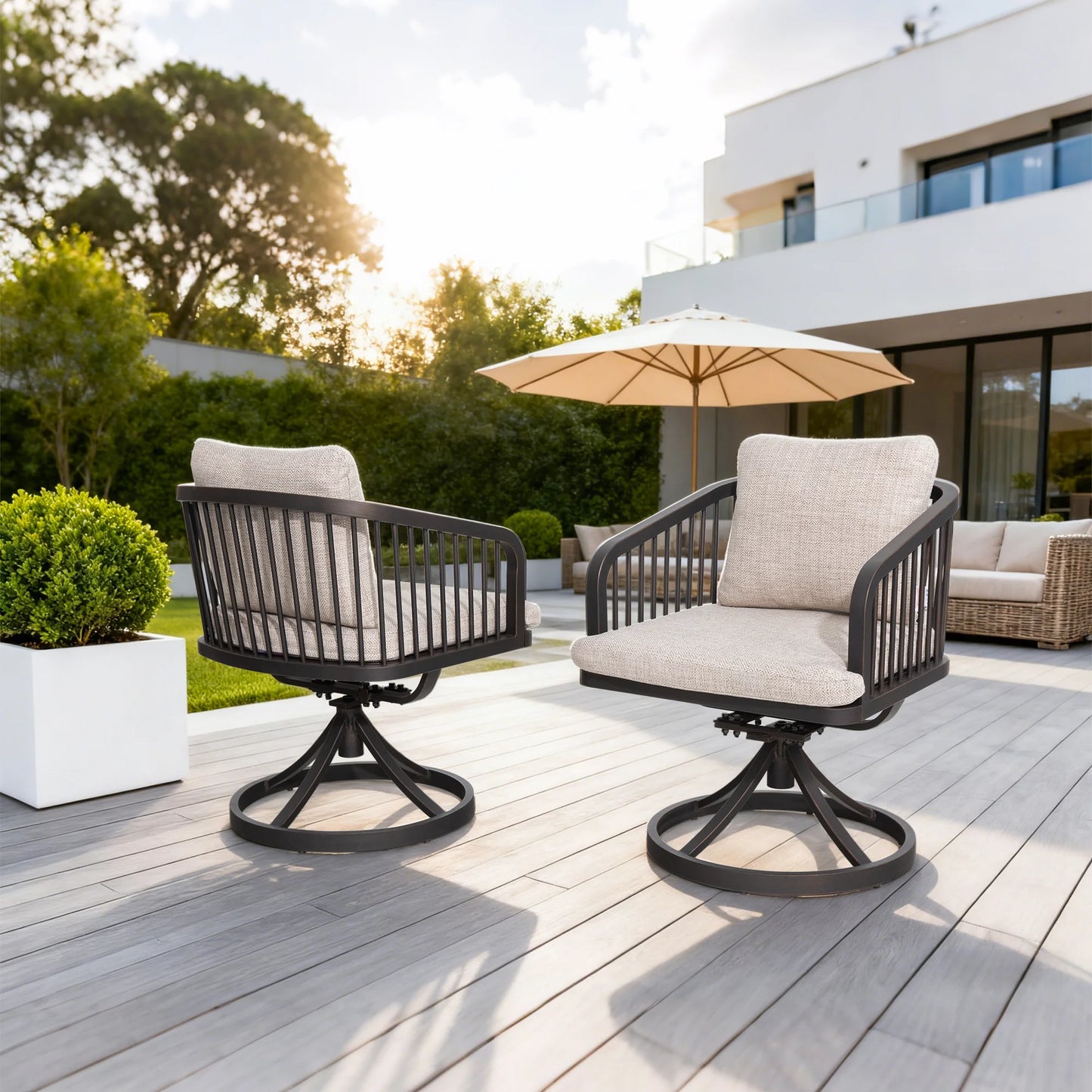 Two outdoor chairs with beige cushions on a wooden deck with a building and trees in the background.