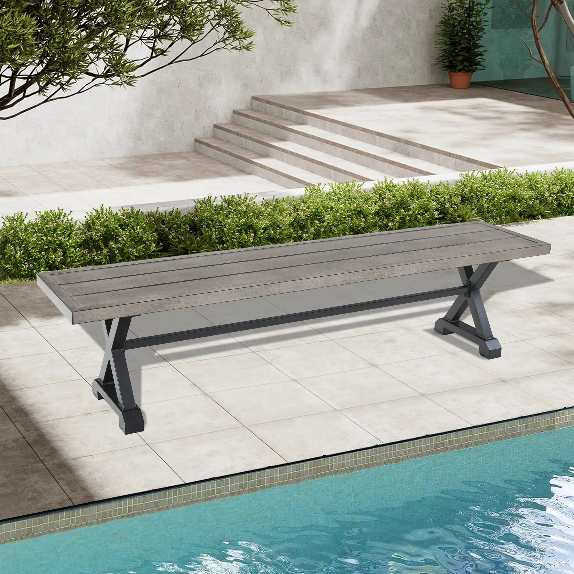 Long wooden bench by a poolside with a garden and steps in the background