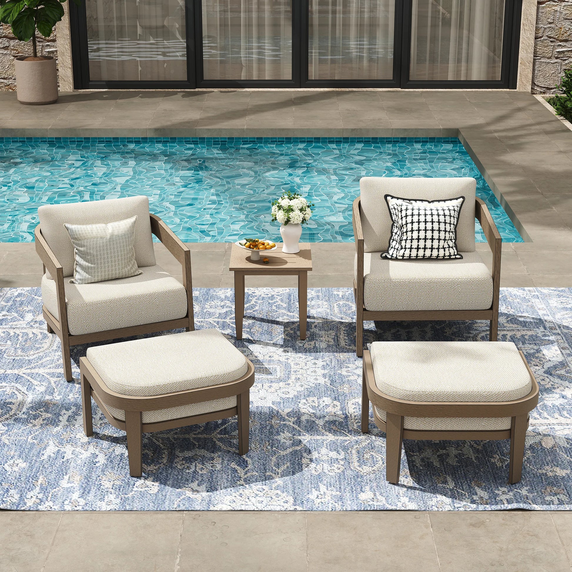 Outdoor furniture set with chairs, ottomans, and a table by a pool.
