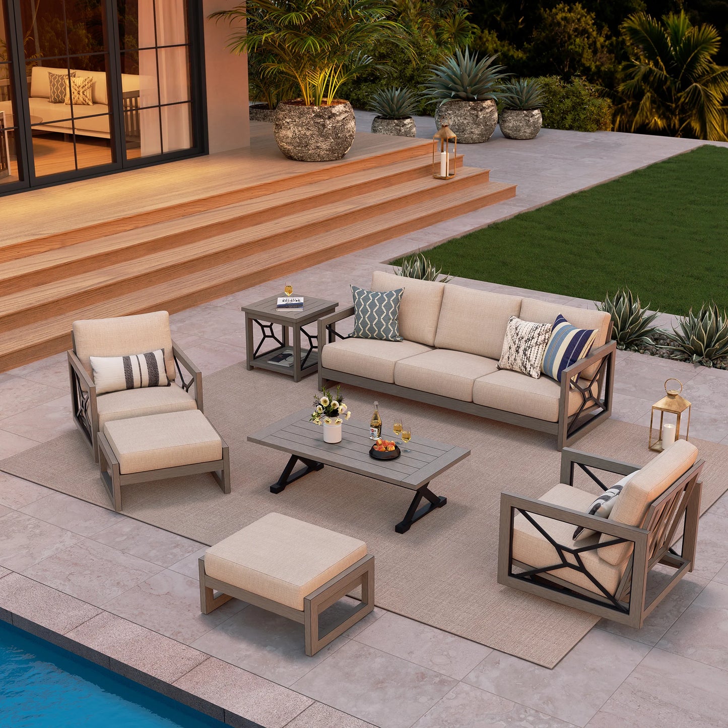 Outdoor patio furniture set with cushions on a patio area near a pool.