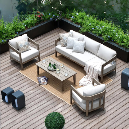 Outdoor patio set with white cushions on a wooden deck, surrounded by greenery.