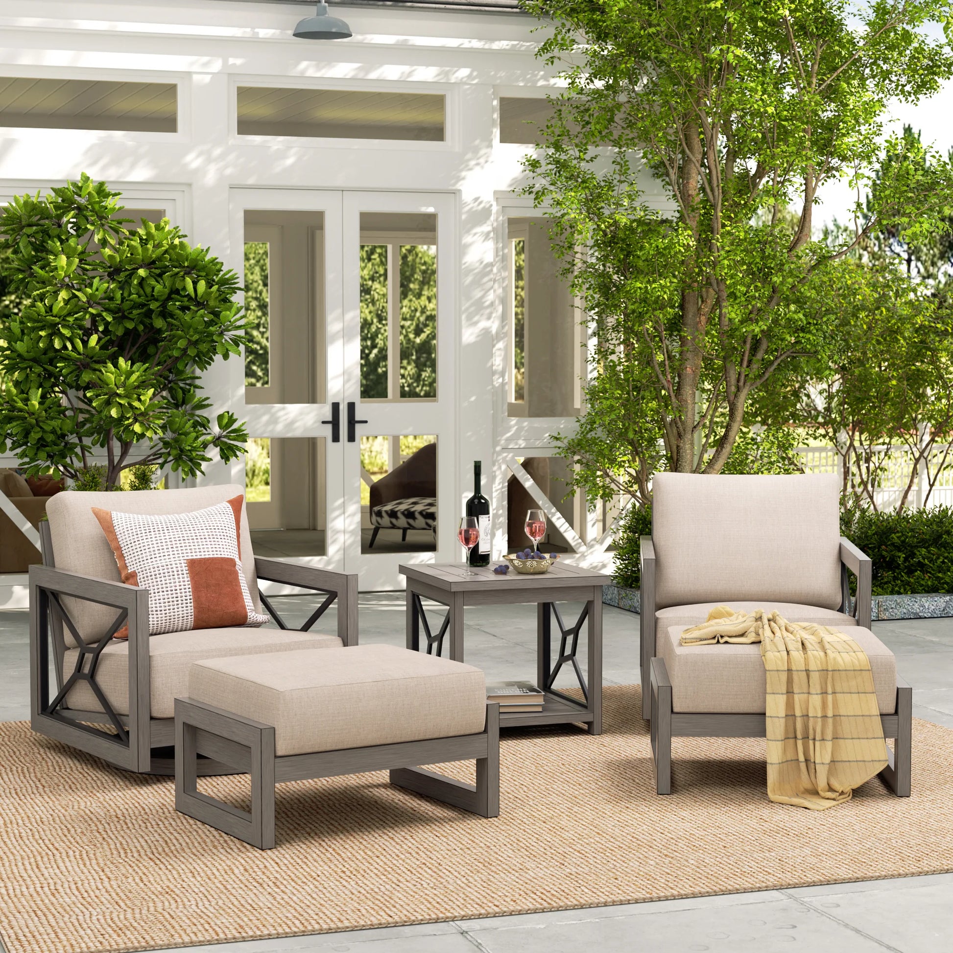 Outdoor patio set with chairs, ottoman, and table on a patio with trees and a building in the background.
