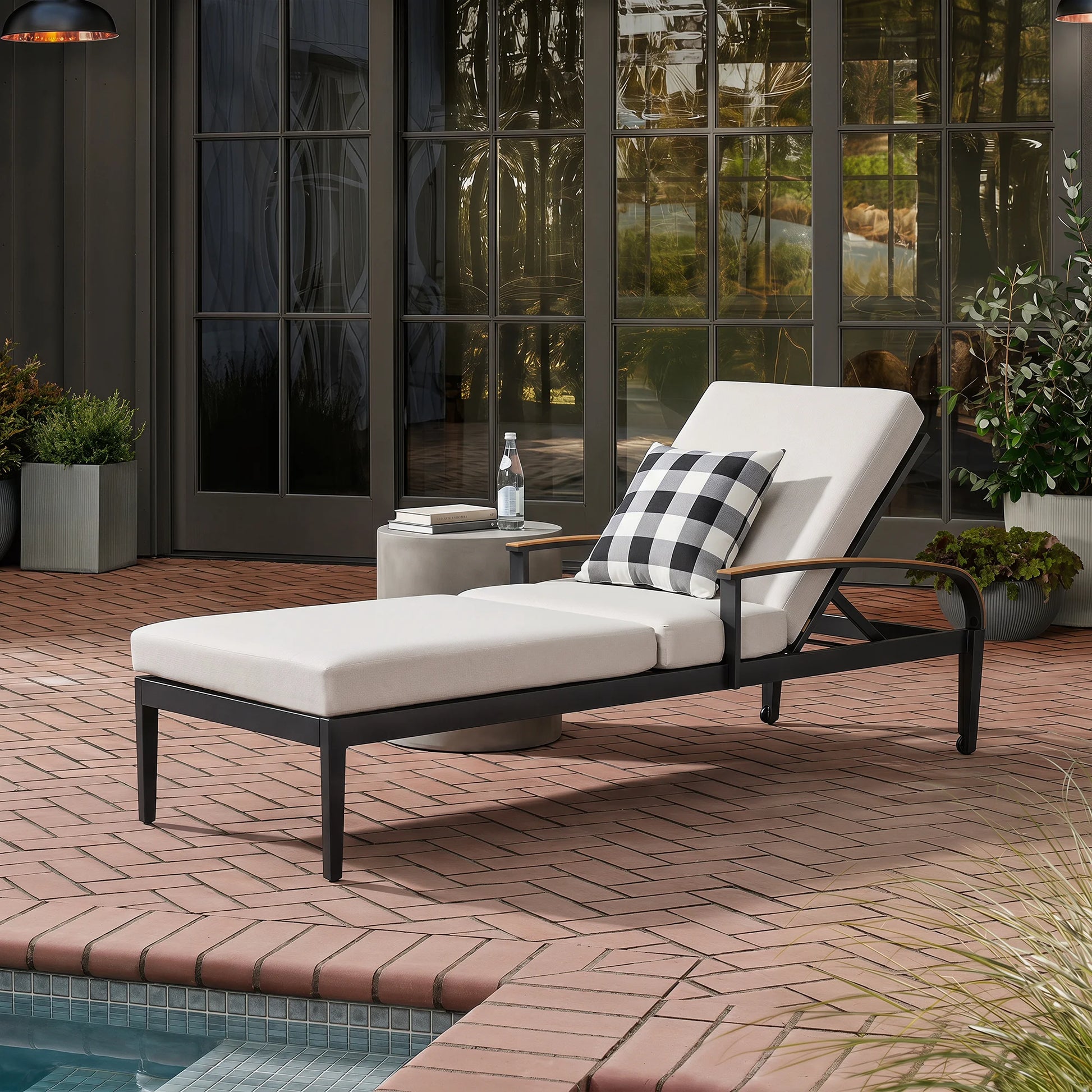 White lounge chair with black metal frame on a patio near a pool