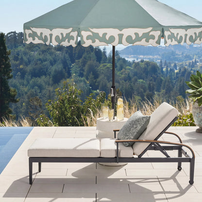 Outdoor lounge chair with umbrella and cushions on a patio with scenic view