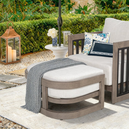 Outdoor patio set with a chair, ottoman, and lantern on a stone patio.