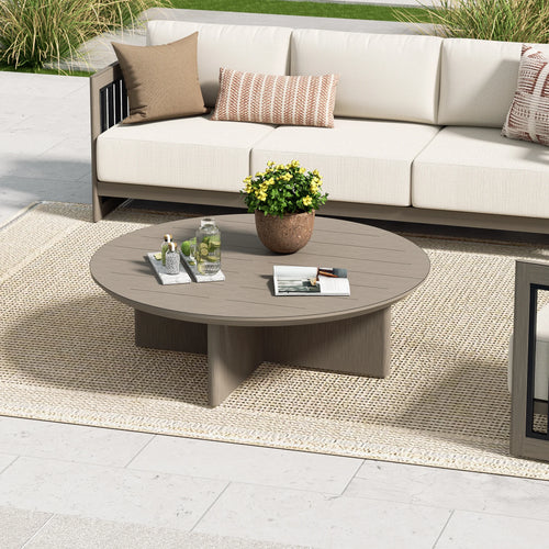 Outdoor patio setting with a round coffee table, sofa, and decorative elements.