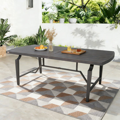Outdoor patio table with a geometric rug and plants in the background