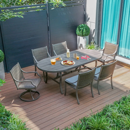 Outdoor patio set with table and chairs on a wooden deck, surrounded by plants and a blue curtain.