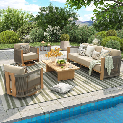 High-end poolside patio featuring a faux-teak outdoor swivel lounge set arranged on a green striped rug with a view of a lush garden.