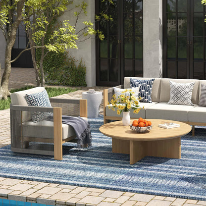 Outdoor patio setting with a sofa, chair, and coffee table on a blue striped rug.