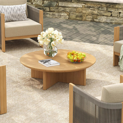 Outdoor patio setting with wooden coffee table, chairs, and decorative elements.