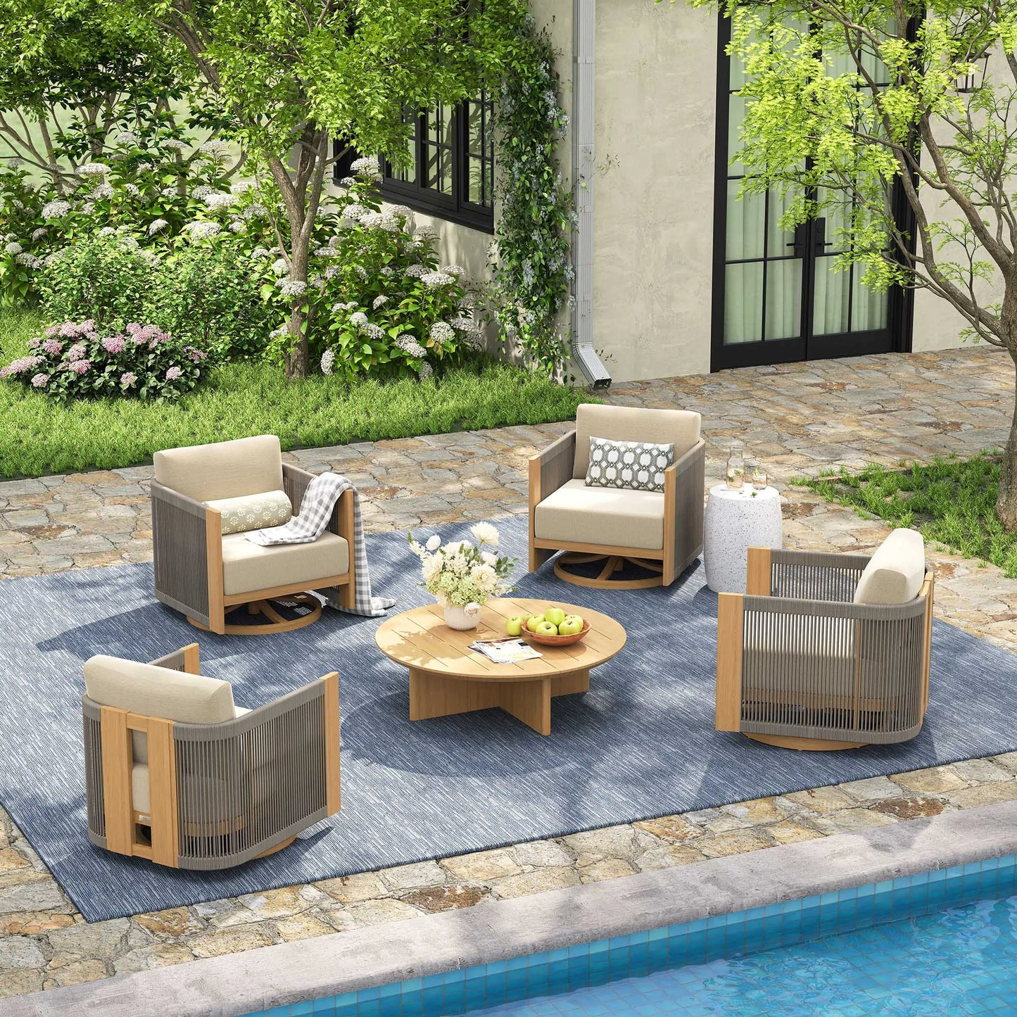 Outdoor patio set with chairs, table, and rug by a poolside.