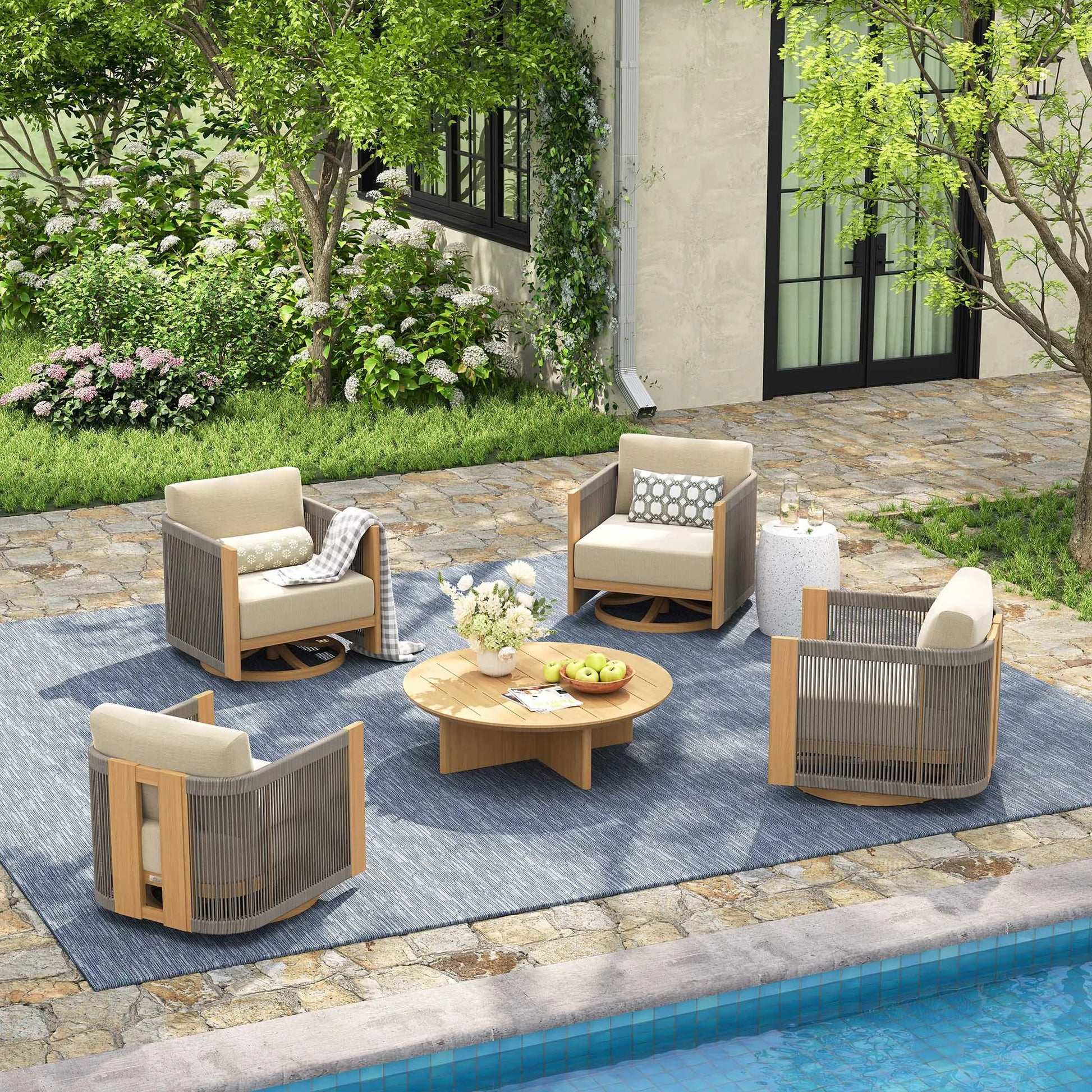 Outdoor patio set with chairs, table, and rug by a poolside.