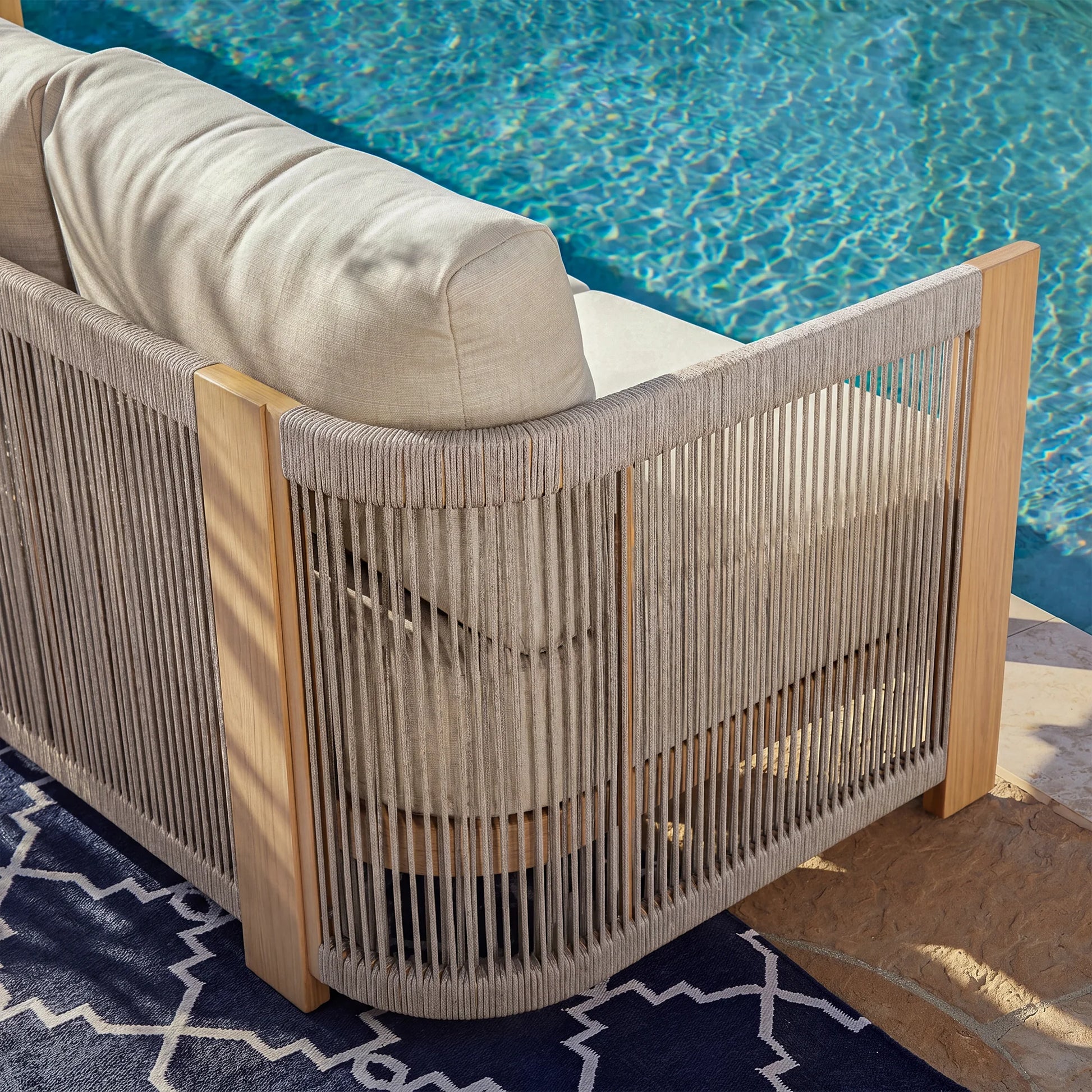 Wicker outdoor chair with beige cushions by a pool