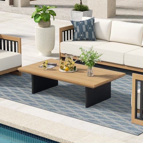 Outdoor patio setting with a wooden coffee table, white sofa, and decorative elements.
