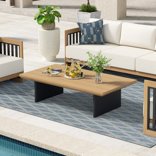 Outdoor patio setting with a wooden coffee table, white sofa, and decorative elements.