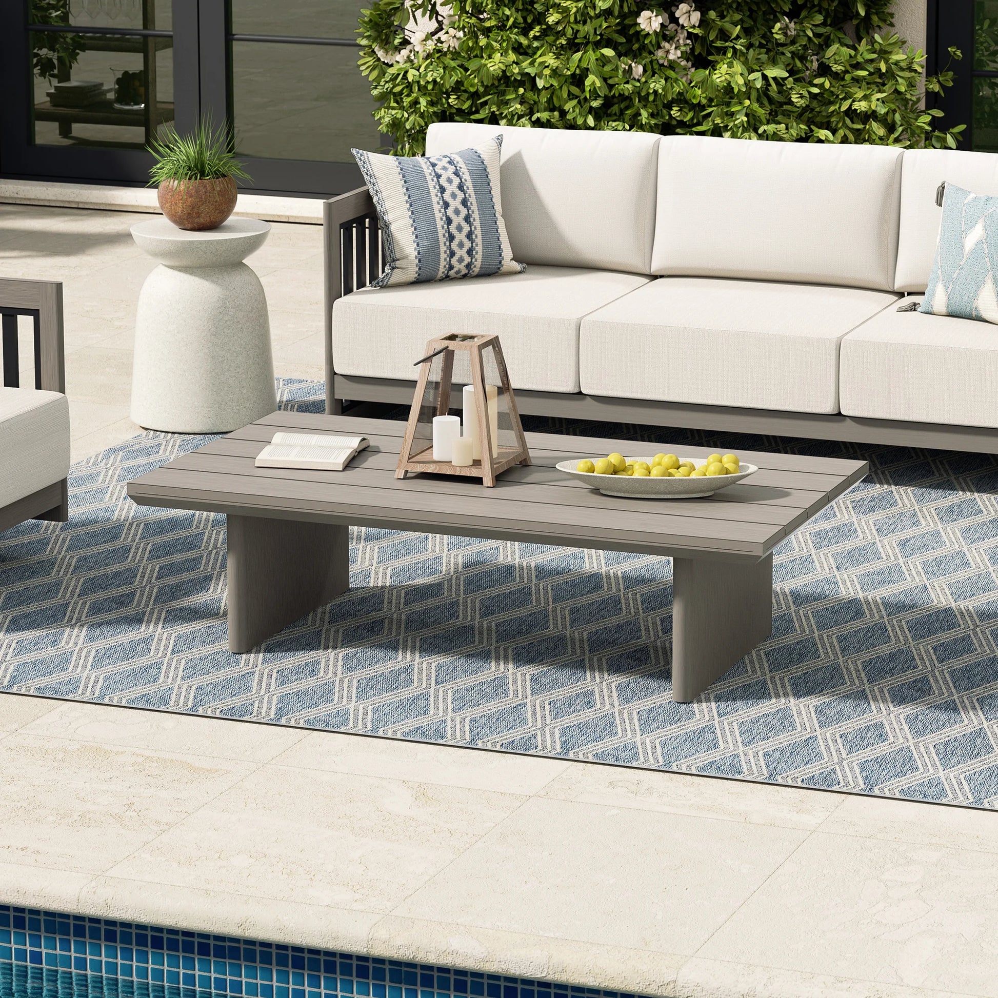 Outdoor patio setting with a white sofa, coffee table, and decorative elements.