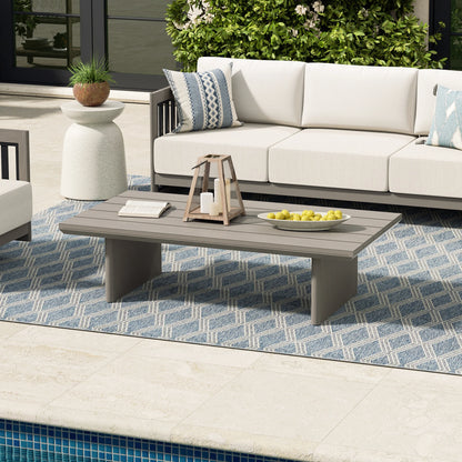 Outdoor patio setting with a white sofa, coffee table, and decorative elements.