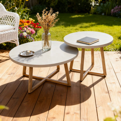 Two round outdoor tables with a vase of flowers and a book on a wooden deck.
