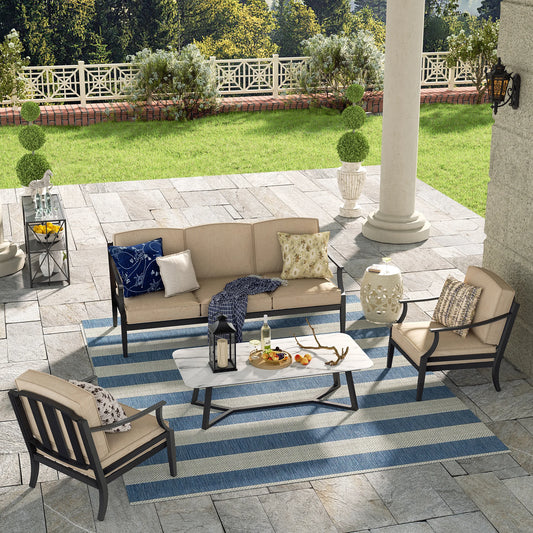 Outdoor patio set with furniture and decor on a striped rug.