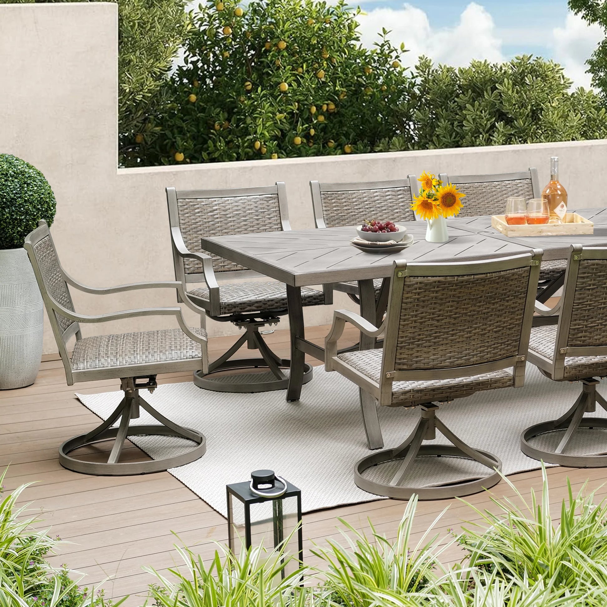 Outdoor patio set with table and chairs on a wooden deck with greenery.