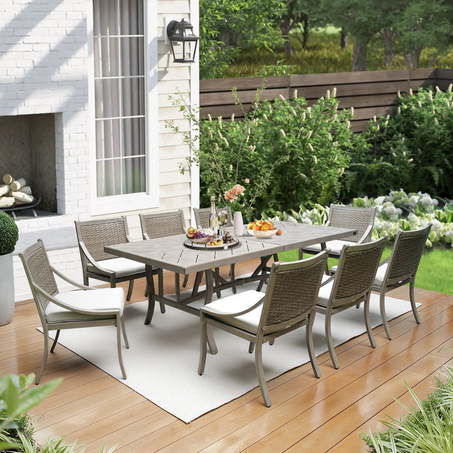 Outdoor patio set with table and chairs on a wooden deck in front of a house.