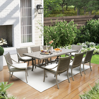 Outdoor patio set with table and chairs on a wooden deck in front of a house.