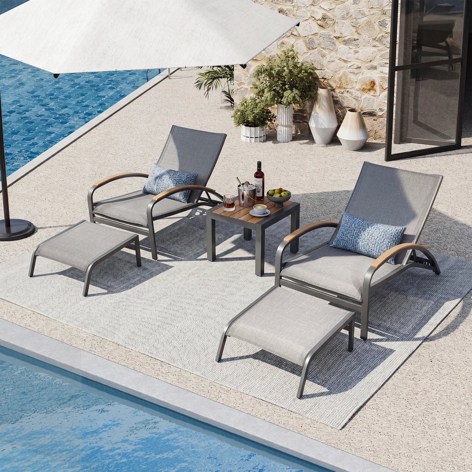 Outdoor patio set with lounge chairs, table, and umbrella by a poolside.
