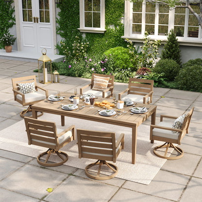 Alcudia 7-piece outdoor dining set with a rectangular faux wood table and six premium 360-degree swivel rocker chairs styled on a warm backyard stone patio.