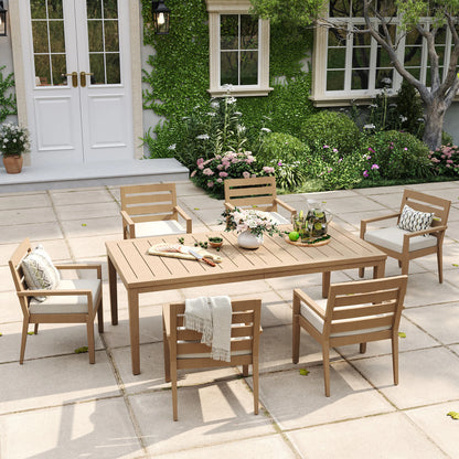 Alcudia 7-piece stationary patio dining set displaying a grand wood-look table and six classic four-leg metal armchairs with thick beige cushions.