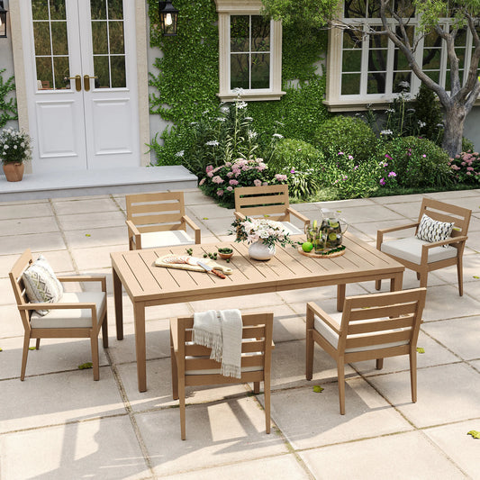 Alcudia 7-piece stationary patio dining set displaying a grand wood-look table and six classic four-leg metal armchairs with thick beige cushions.