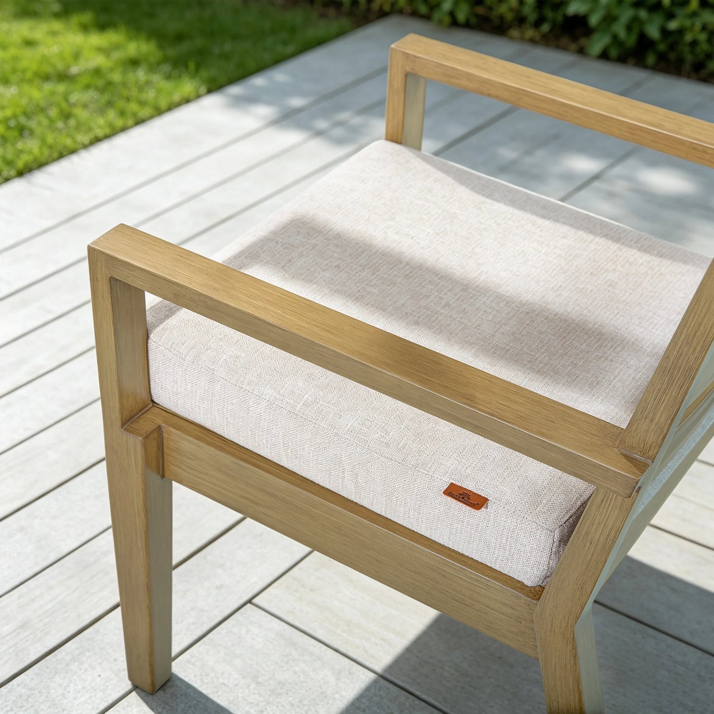 High-angle close-up of Alcudia aluminum patio armchair featuring textured beige cushion and hand-brushed faux oak wood armrest.