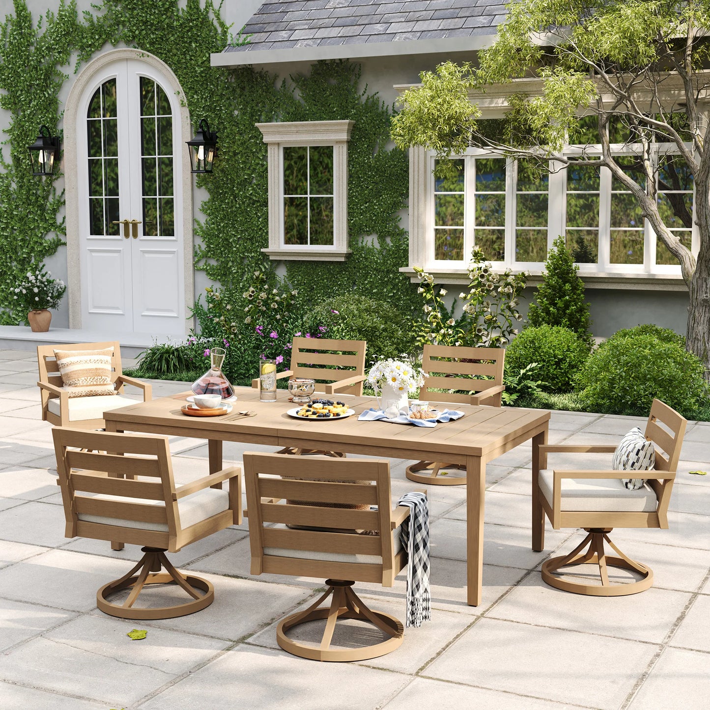An eye-level view of the Alcudia aluminum patio dining set featuring six swivel rocker armchairs arranged for an alfresco gathering on a paved courtyard.