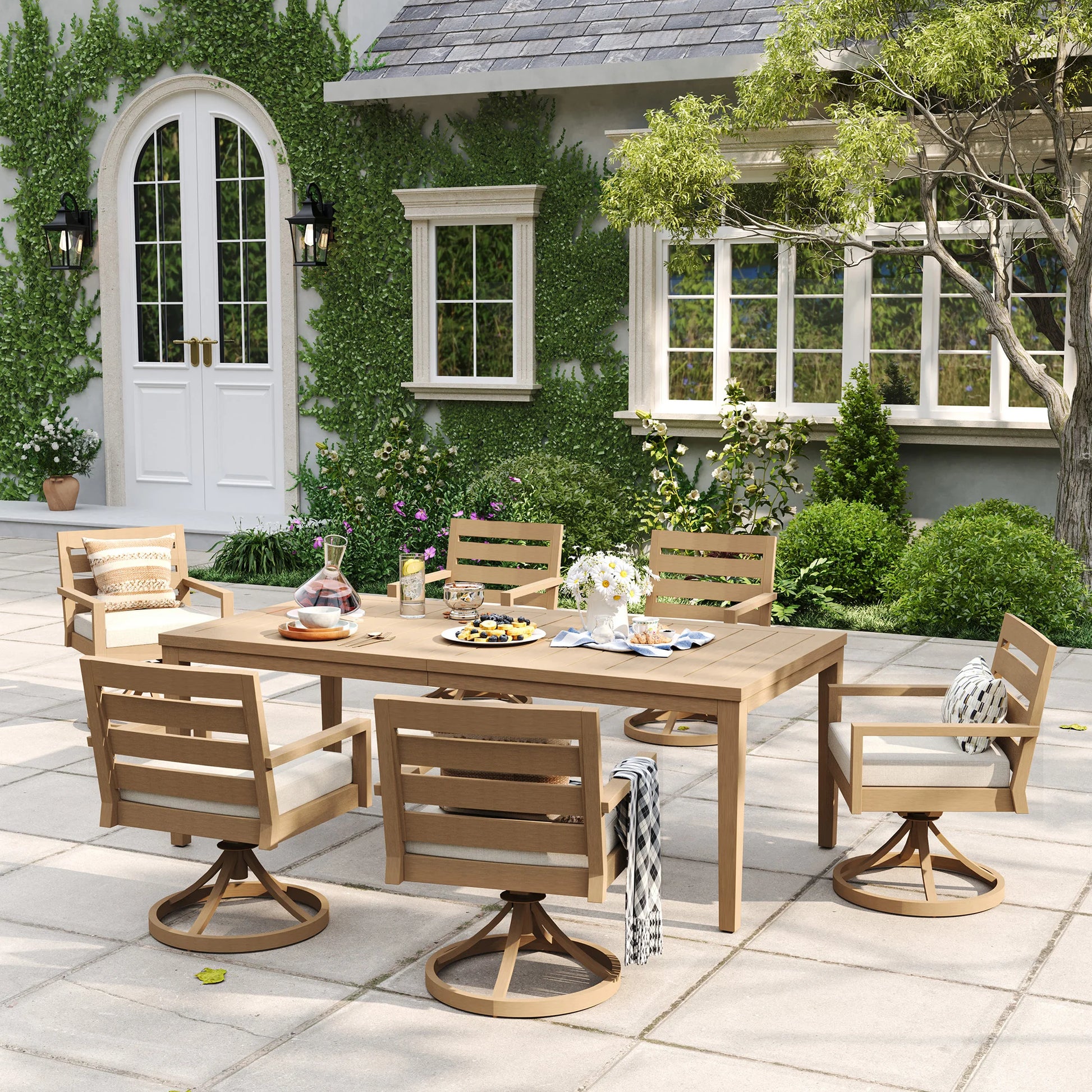 An eye-level view of the Alcudia aluminum patio dining set featuring six swivel rocker armchairs arranged for an alfresco gathering on a paved courtyard.