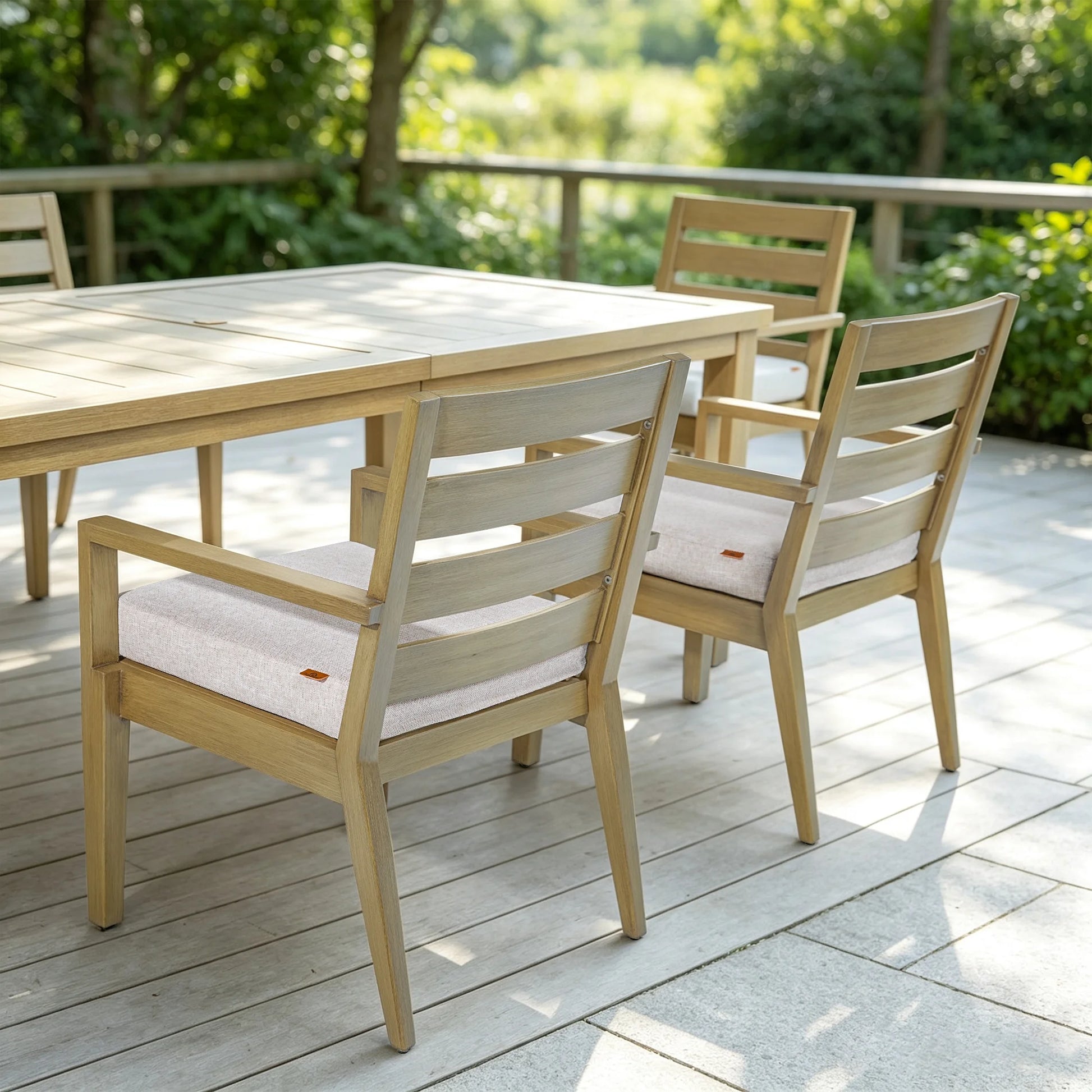 Alcudia faux wood aluminum dining table and matching chairs with cushions arranged on a sunny backyard wooden deck.