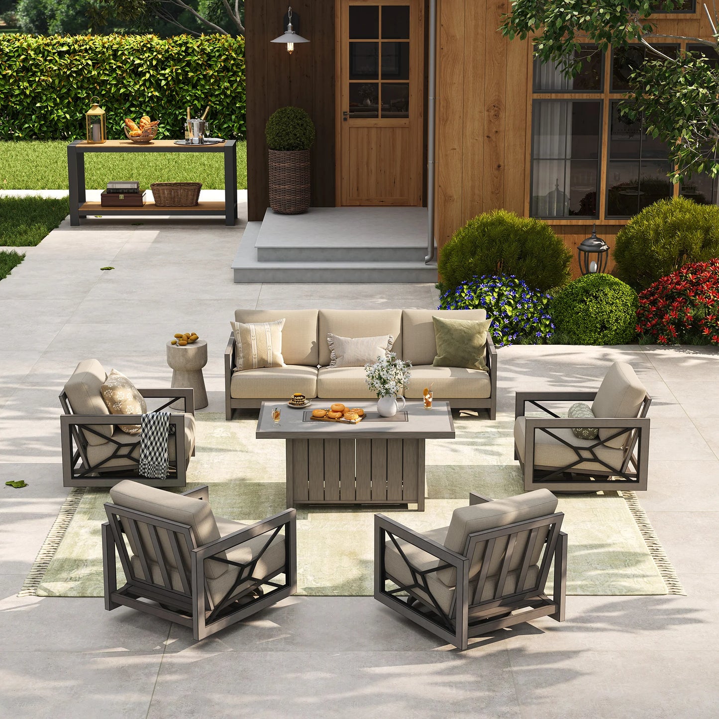 A bright poolside patio showcasing an all-weather outdoor living room layout with the Marindo 7-passenger aluminum sofa set, featuring four swivel chairs arranged over a green-tinted rug during the day.