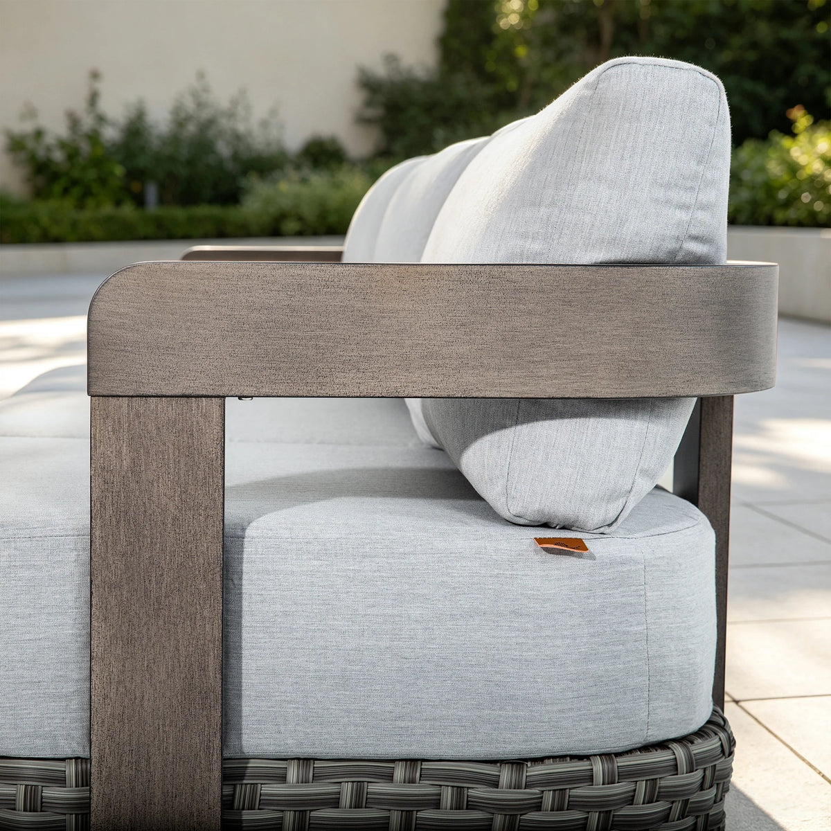 Side view detail showing the seamless wood-grain painted finish on the wide modern aluminum armrest of the Manarola sofa.