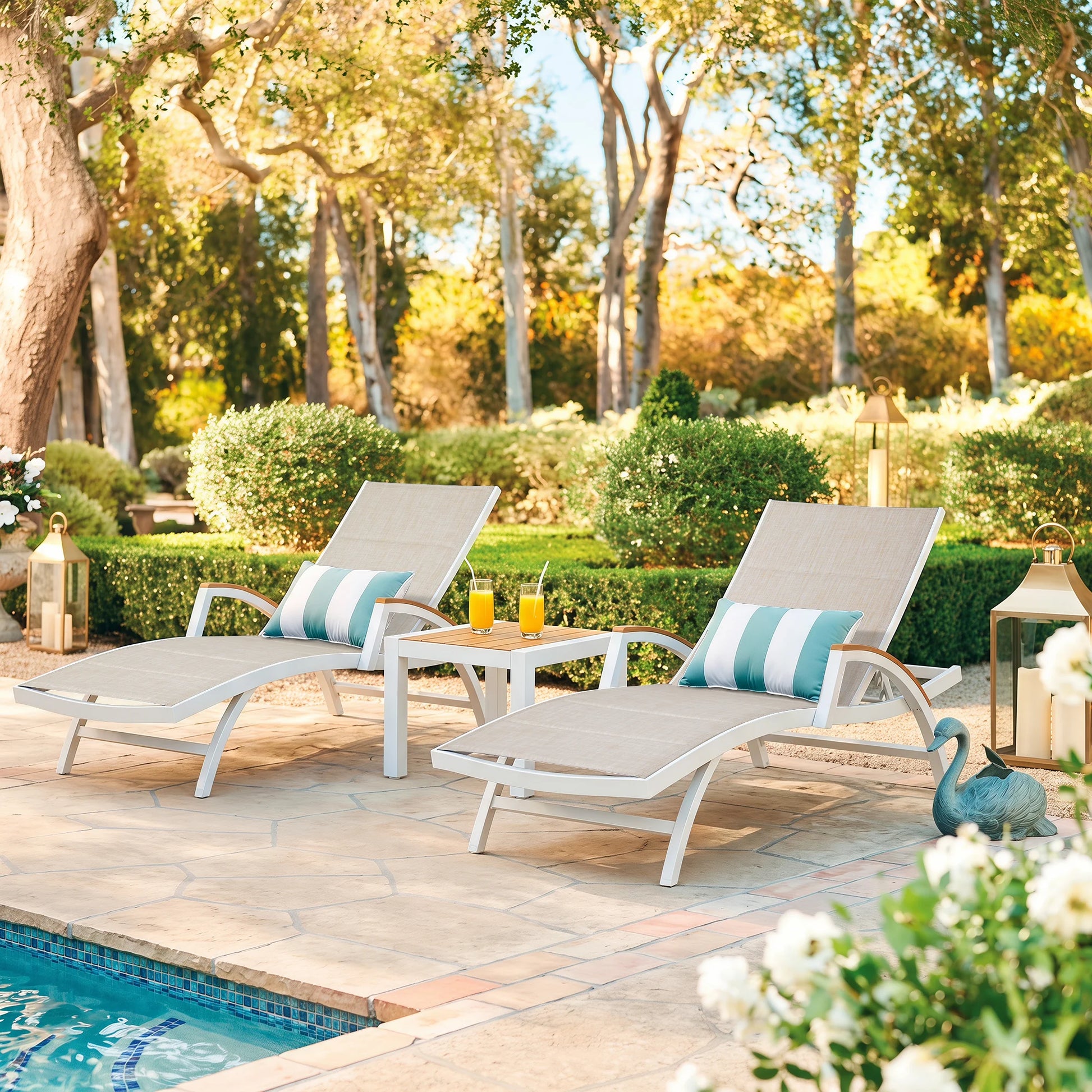 Chambray luxury patio lounge chairs set arranged symmetrically on a stone terrace overlooking a lush garden and a private swimming pool.