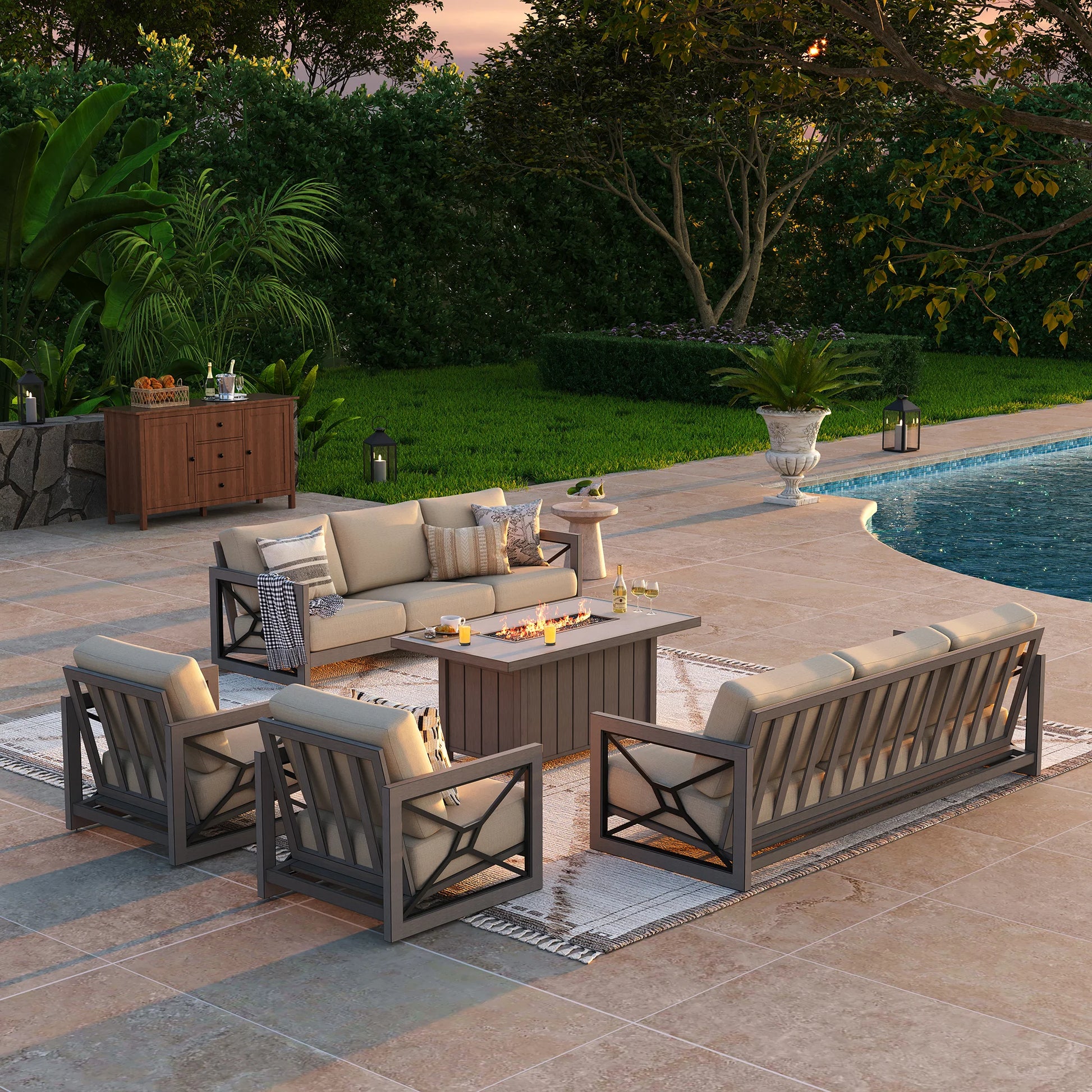 An elegant backyard entertaining space at sunset, displaying the Marindo 8-guest patio collection with a roaring fire pit table illuminating a sofa and two fixed club chairs.