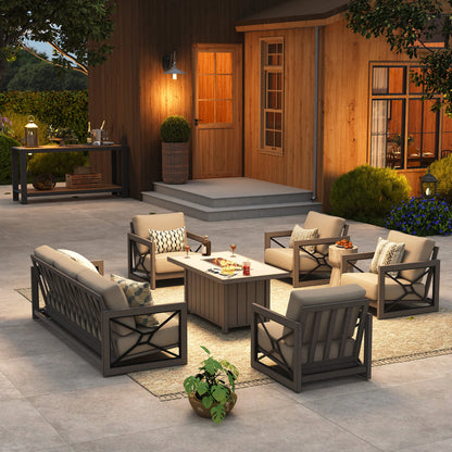 Upscale backyard gathering setting at twilight featuring the Marindo 7-person patio conversation set, with cozy amber flames from the fire pit table illuminating a warm wood cabin background.