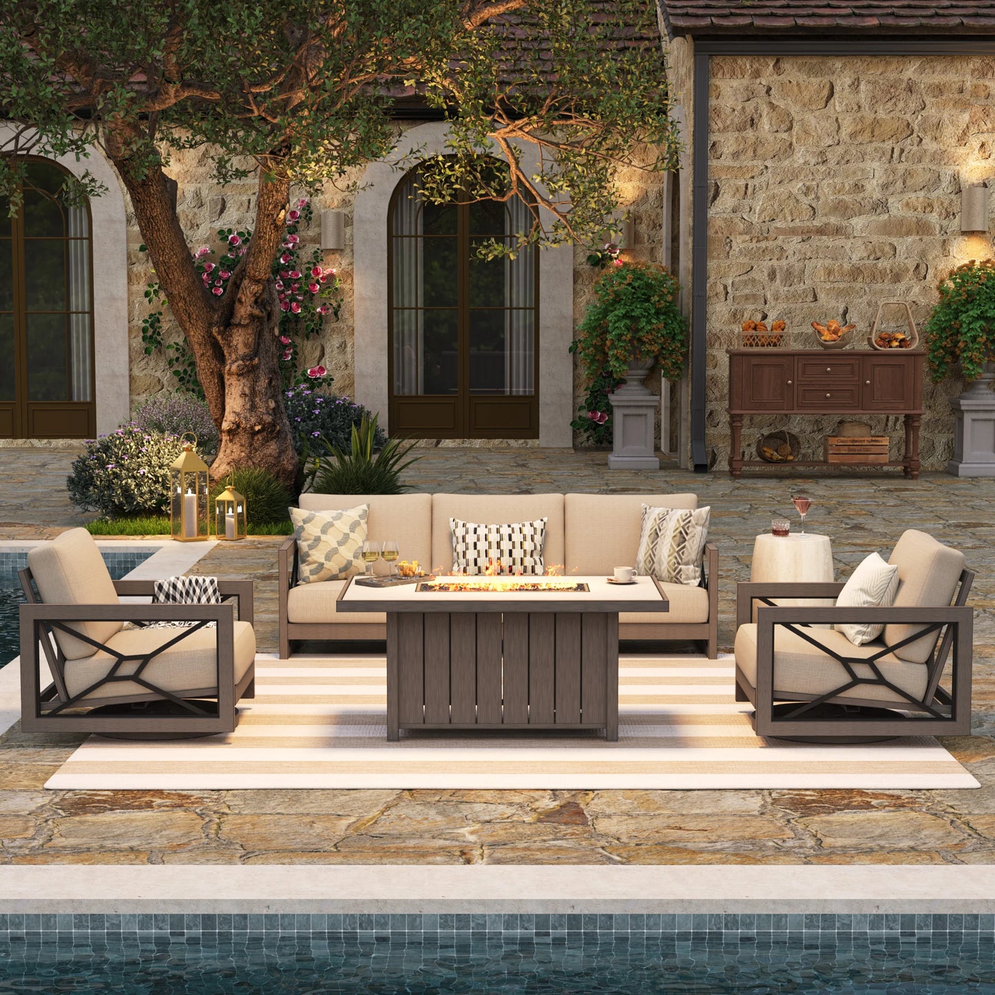 Upscale backyard patio at night featuring the Marindo aluminum outdoor seating set, showcasing amber flames glowing from the 50,000 BTU stainless steel fire pit table and warm ambient lights.