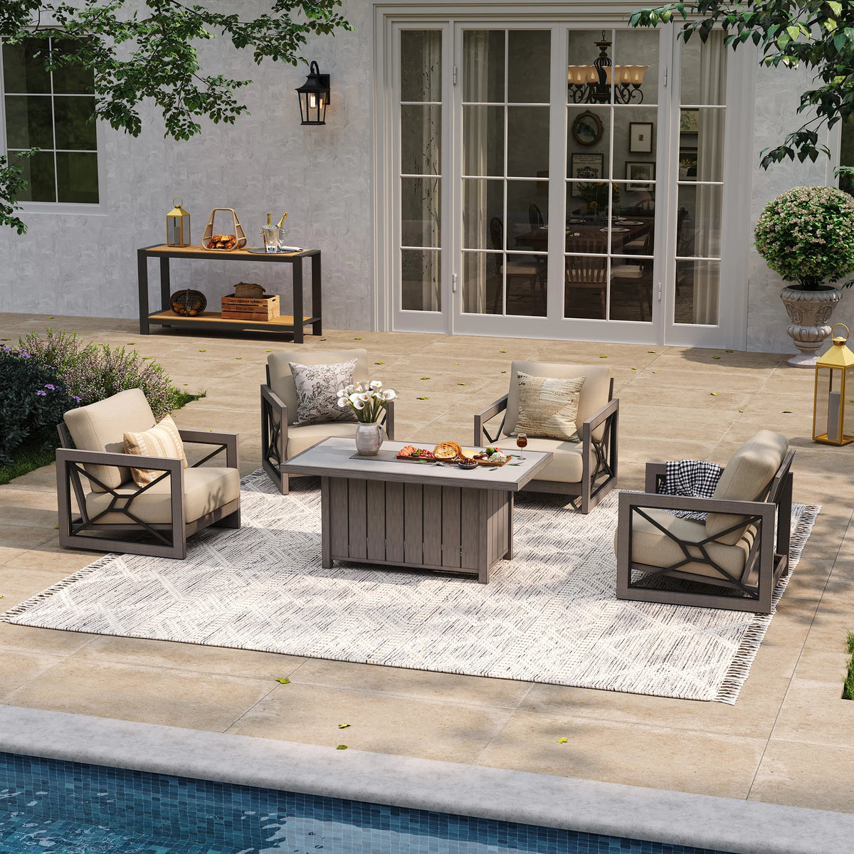 A bright resort-style poolside terrace providing backyard gathering inspiration, highlighting the Marindo 4-person wood-look aluminum seating layout with stationary club chairs over a white patterned rug during the day.