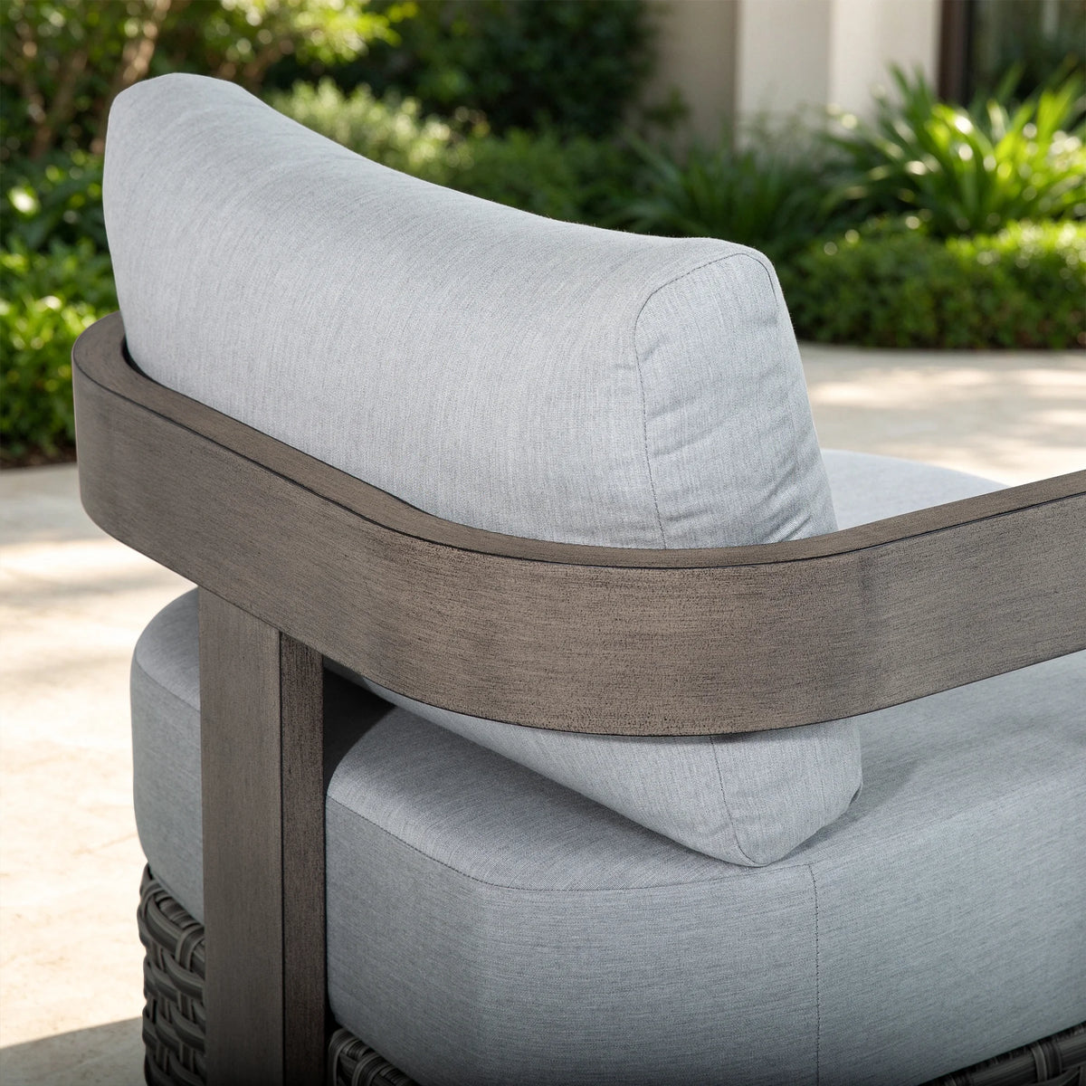 Studio shot of the rear angle of the Manarola fixed patio lounge chair, displaying its bold geometric structure and woven wicker skirt base.