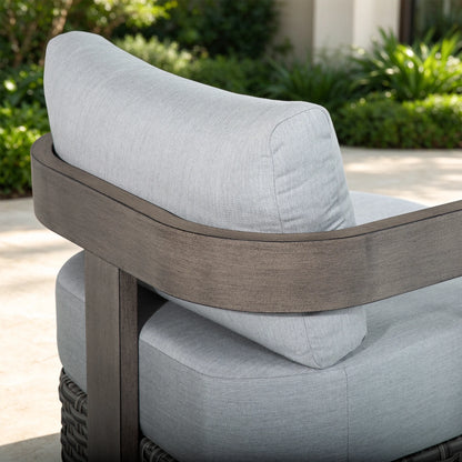 Studio shot of the rear angle of the Manarola fixed patio lounge chair, displaying its bold geometric structure and woven wicker skirt base.