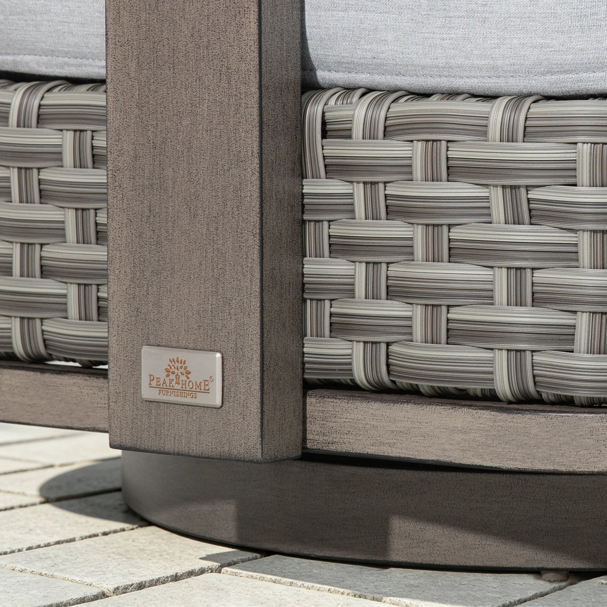 Close-up of the Peak Home Furnishings metal logo plate embedded on the weathered-wood finish aluminum frame.