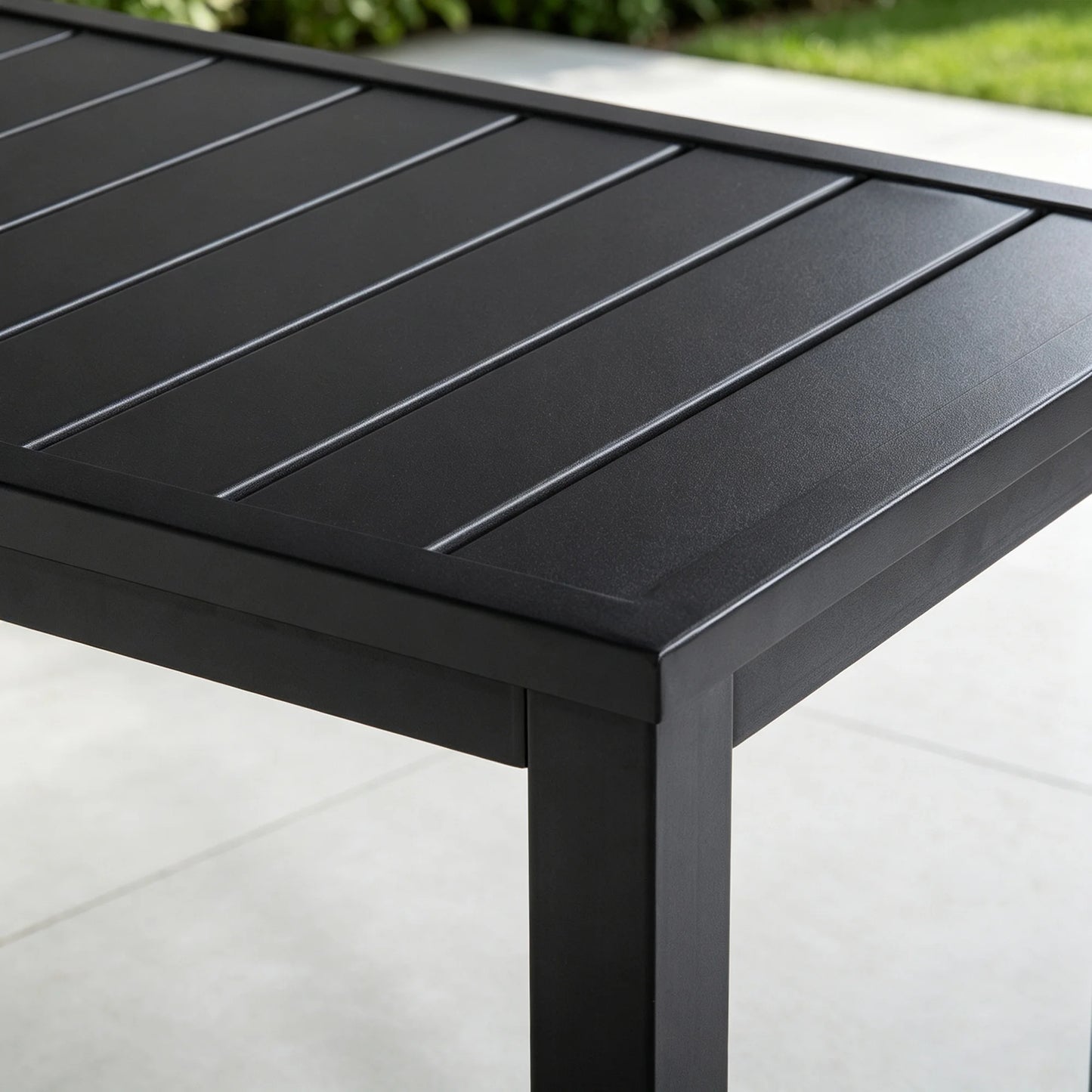 Detail shot of the top corner joint of Saporta table, highlighting the sleek matte black finish and sturdy slatted metal construction.