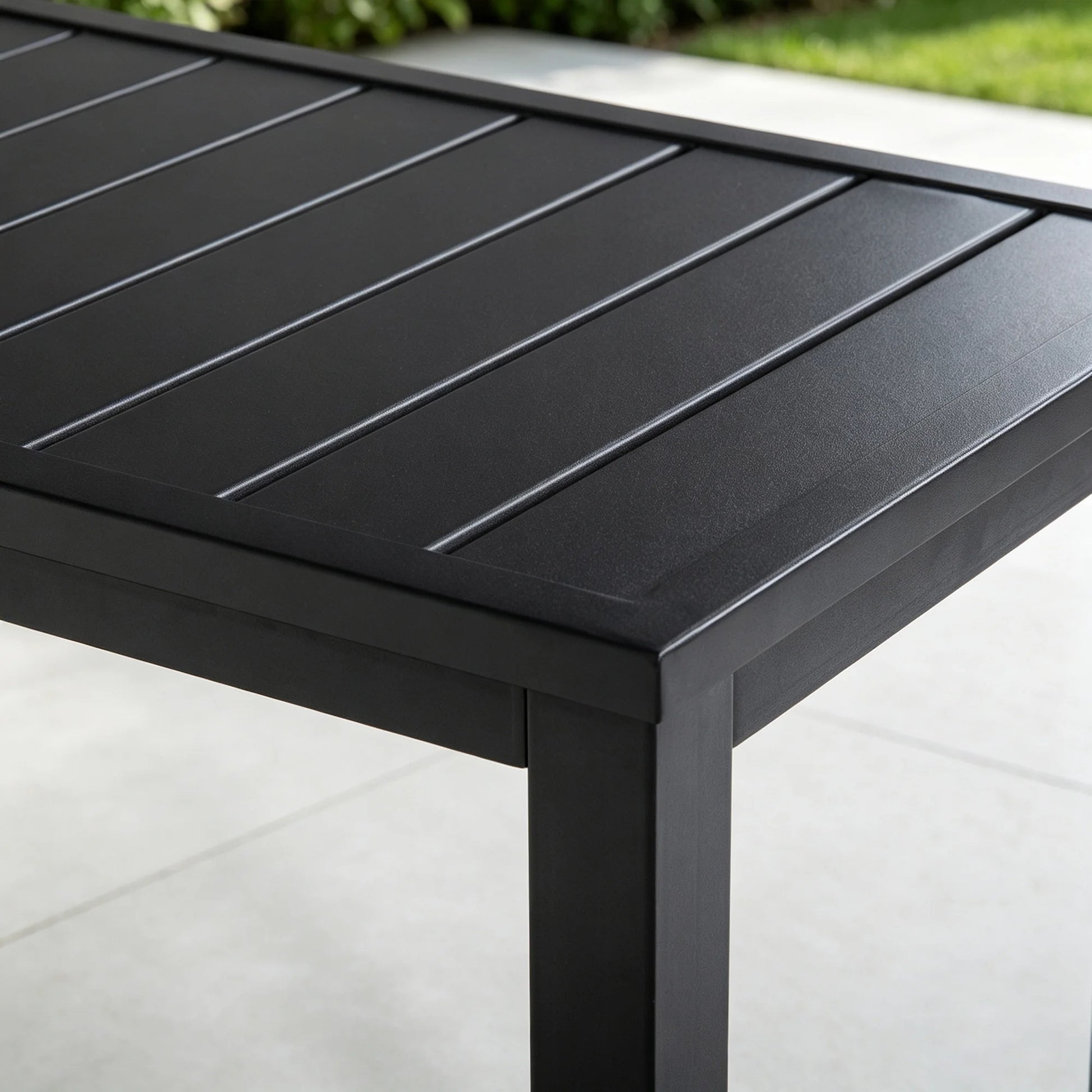 Detail shot of the top corner joint of Saporta table, highlighting the sleek matte black finish and sturdy slatted metal construction.