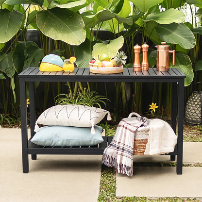 Front view of Saporta outdoor kitchen prep station table with copper pitchers, fresh fruits, and outdoor pillows against a green tropical garden backdrop.
